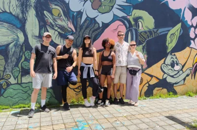 Group of students participating in a cultural activity in front of a mural in Medellín as part of a Spanish immersion program.